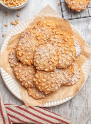 A plate of pignoli cookies, dusted with powdered sugar.