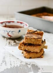 A stack of 3 slices of pumpkin protein cake with the remaining cake in a pan behind the stack