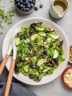 A salad bowl with salad and matching utensils.