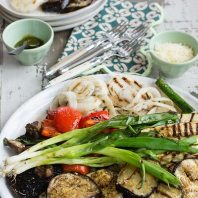 Platter of grilled vegetables with plate of veggies in background