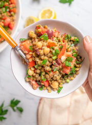 Holding a bowl of salad and a fork.