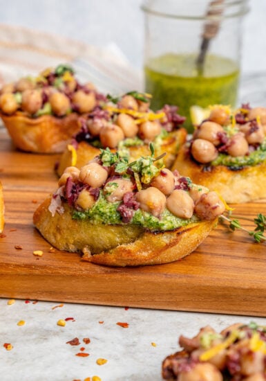 Close-up of chickpea bruschetta with lemon zest and fresh thyme on top.